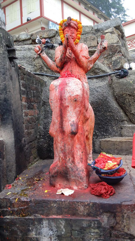 A goddess sitting on a cow at Kamakhya temple immersed in vermillion